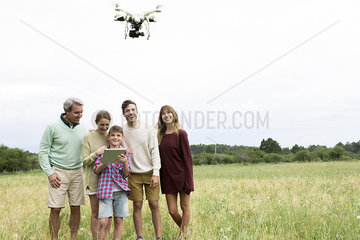 Multi-generation family playing with drone in field