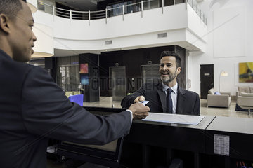 Hotel receptionist handing keycard to business traveler