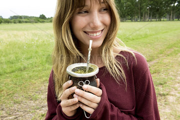 Young woman drinking mate in gourd