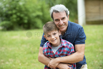 Grandfather embracing grandson outdoors  portrait