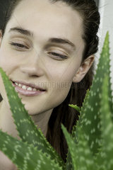 Young woman looking at aloe vera plant