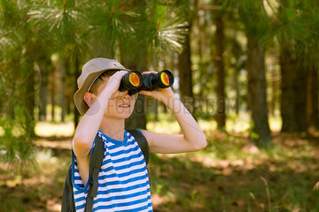 Boy using binoculars in woods