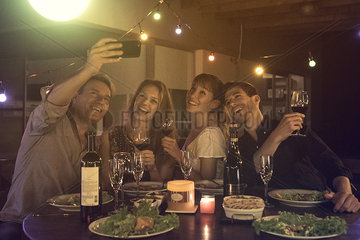 Friends posing for group selfie at dinner party