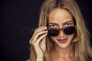 Young woman peeking over top of sunglasses  portrait