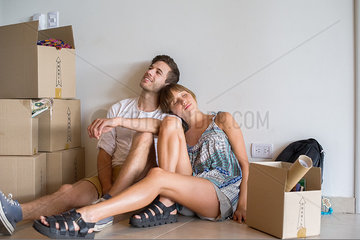 Young couple sitting in new house with cardboard boxes