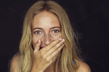 Young woman laughing with hand over mouth