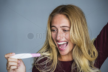 Young woman celebrating results of pregnancy test