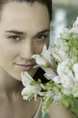 Young woman smelling bouquet of fresh flowers