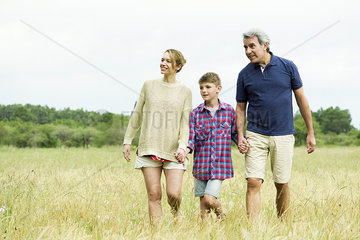 Family with one child on walk together in open field