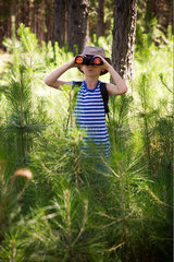 Boy using binoculars in woods