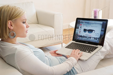 Hamburg  Deutschland  eine junge Frau mit einem MacBook im Wohnzimmer