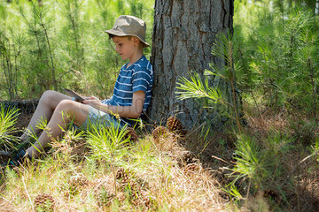 Boy using digital tablet in woods