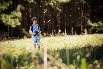 Boy walking through meadow with binoculars