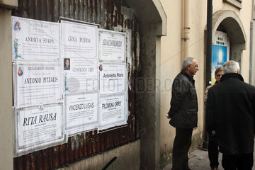 Oristano  Italien  aeltere Personen stehen neben einer Plakatwand und unterhalten sich