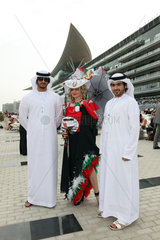 Dubai  Vereinigte Arabische Emirate  elegant gekleidete Frau und Maenner in Landestracht beim Pferderennen