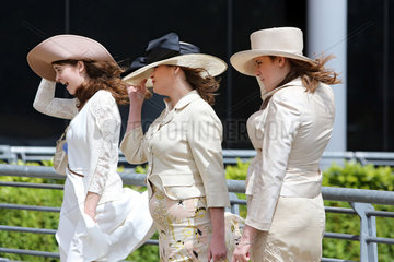 Ascot  Grossbritannien  elegant gekleidete Frauen halten bei starkem Wind ihre Huete fest