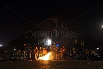 Utrecht  Niederlande  Menschen stehen nachts auf der Strasse vor einem kleinen Feuer