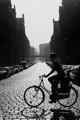 Berlin  Deutschland  Frau ueberquert auf dem Fahrrad die Strasse