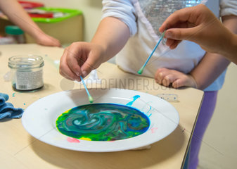 Kinder beim Spiel mit fluessigen Farben in einer Kindertagesstaette