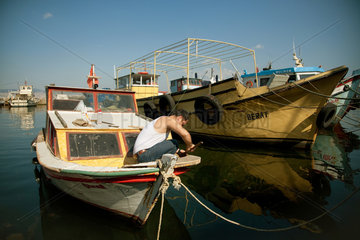 Heybeliada  Istanbul  Tuerkei  ein Mann repariert sein Boot im Hafen von Heybeliada
