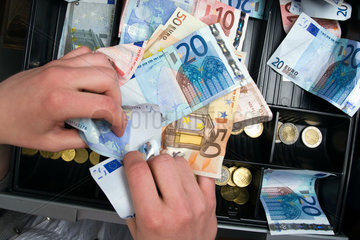 Berlin  Deutschland  Haende greifen nach Geld in der Kasse