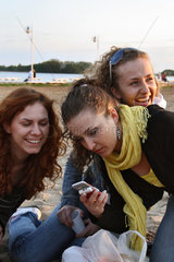 Skorzecin  Polen  Studentinnen mit Handy an einem See