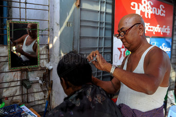 Yangon  Myanmar  Strassenbarbier schneidet einem Kunden die Haare