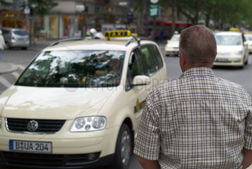 Berlin  Deutschland  Mann betrachtet ein vorbeifahrendes Taxi