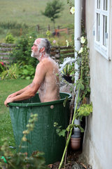 Neu Kaetwin  Deutschland  Mann badet in einer Regenwassertonne