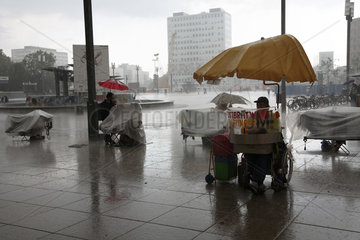 Berlin  Deutschland  Bratwurstverkaeufer und Souvenirhaendler stehen im Regen