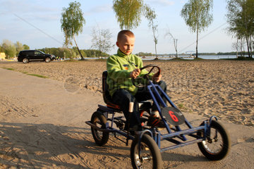 Skorzecin  Polen  Junge auf Kettcar an einem See