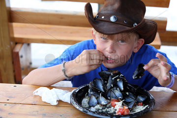 Saint Petersburg  USA  Junge mit Cowboyhut isst frische Miesmuscheln