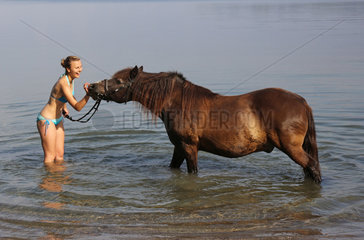 Schwerin  Deutschland  junge Frau steht mit ihrem Pony im Schweriner See