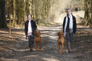 Hamburg  Deutschland  zwei Schwestern gehen mit Hunden im Wald spazieren
