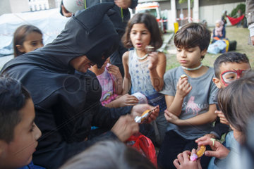 Berlin  Deutschland  Oemer Aslan im Batman Kostuem spielt mit Kindern von Fluechtlingen vor dem Lageso