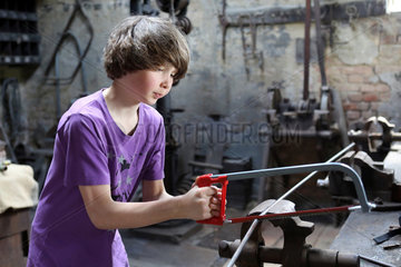 Cammin  Deutschland  Junge bearbeitet eine Eisenstange mit einer Saege