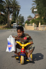 Nikosia  Tuerkische Republik Nordzypern  ein Junge in Militaerkleidung auf einem Dreirad