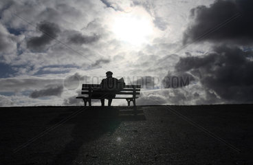 Hannover  alter Mann sitzt vor dramatischem Wolkenhimmel lesend auf einer Bank