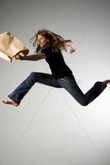 Freiburg  Deutschland  junge Frau mit Jeans und Einkaufstuete bei einem Luftsprung