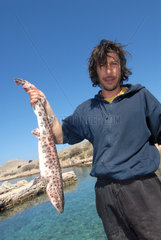 Sibenik  Kroatien  ein Fischer zeigt seine Beute auf einer kleinen Insel vor Sibenik