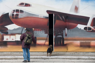 Dresden  Deutschland  Mann mit Hund vor einer Graffiti-Wand mit Flugzeugmotiv und offener Tuer