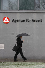 Berlin  Deutschland  Frau mit Regenschirm vor der Agentur fuer Arbeit