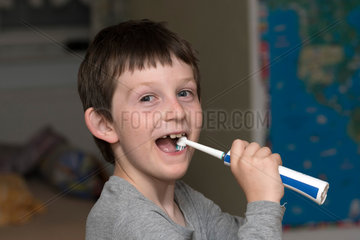 Berlin  Deutschland  Junge putzt sich mit einer elektrischen Zahnbuerste die Zaehne