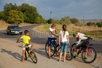 Republik Moldau  Kinder mit Fahrraedern an einer Landtrasse schlagen die Zeit tot