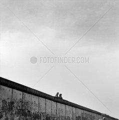 Berlin  DDR  zwei Grenzsoldaten schauen ueber die Berliner Mauer