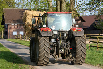 Soltau  Deutschland  Traktor transportiert einen Strohballen