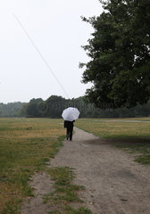 Berlin  Deutschland  Spaziergaengerin mit Regenschirm im Park