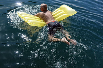 Capodimonte  Italien  Mann schwimmt auf seiner Luftmatraze in einem See