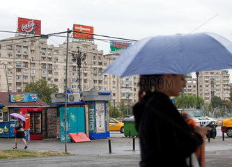 Bukarest  Rumaenien  Passanten und Wohnhaeuser mit Werbetafeln am Platz der Einheit