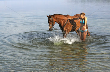 Schwerin  Deutschland  junge Frau planscht mit ihrem Pferd im Schweriner See